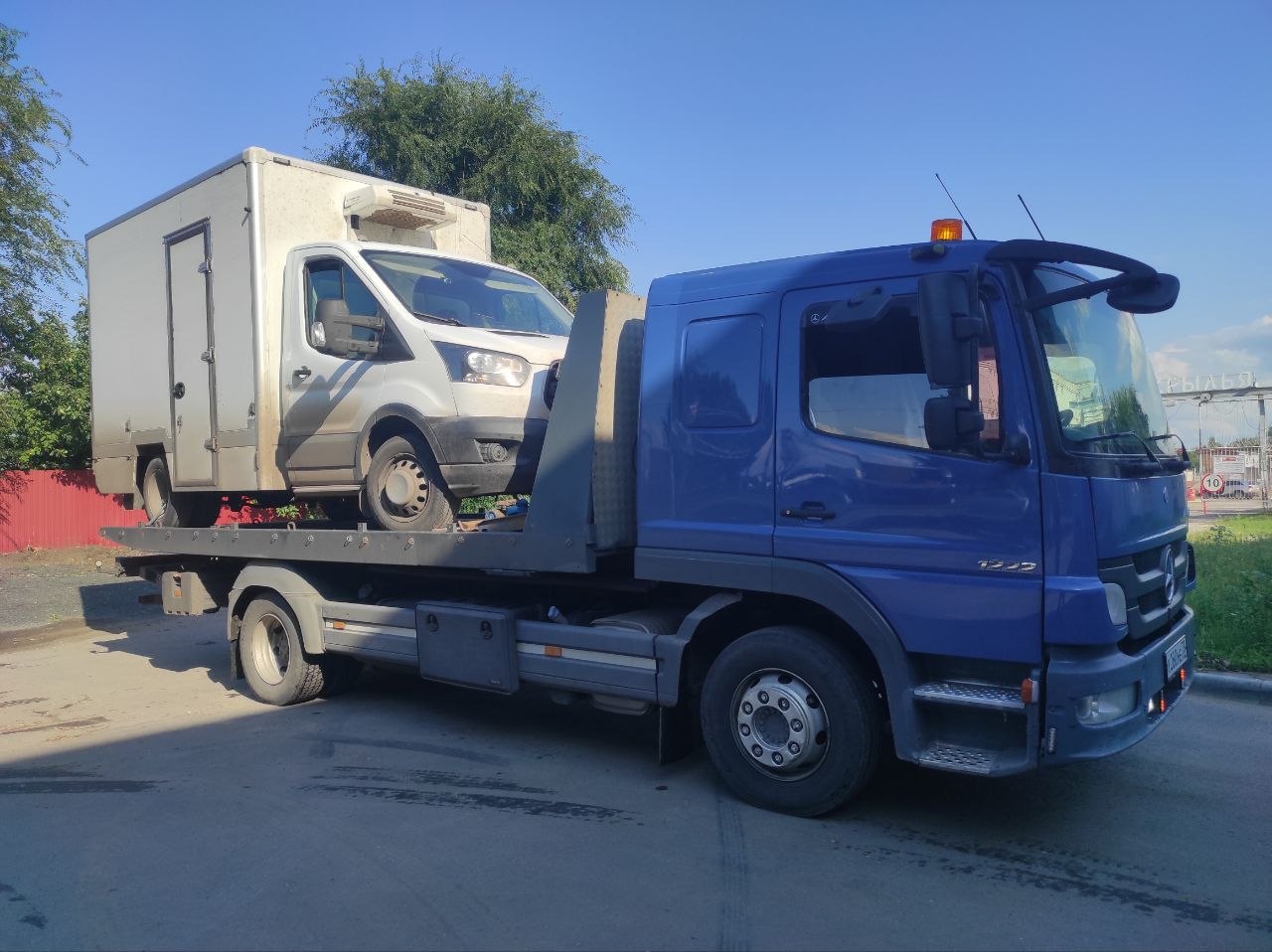 Эвакуатор везёт легковой автомобиль по трассе на рассвете